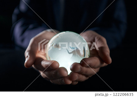 A man holds a glowing globe in his hands. close-up on a black background A man holds a glowing globe in his hands. close-up on a black background 122206635