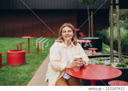 Happy redhead 30s Woman holding brown paper cup of coffee on public park background, Coffee to go on the city street. Food, rest, Take away concept. 122207412