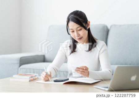 レシートと睨めっこするミドル女性 122207759