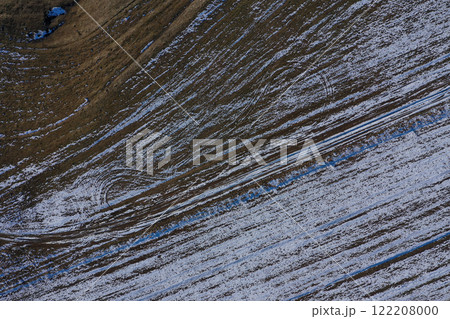 Aerial view of snow covered winter agricultural field with tractor trace 122208000