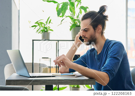 Serious young handsome man talking on mobile phone Serious young handsome man talking on mobile phone 122208163
