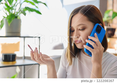 Headshot portrait of young serious woman talking on mobile phone in coworking 122208167