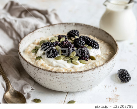 Creamy bowl of porridge topped with fresh blackberries and seeds, perfect for breakfast Creamy bowl of porridge topped with fresh blackberries and seeds, perfect for breakfast 122208789