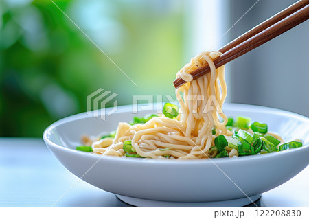 Instant noodles with green onion and chopsticks in a bowl on the table 122208830