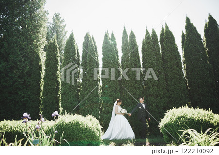 Happy wedding couple walking in a botanical park Happy wedding couple walking in a botanical park 122210092