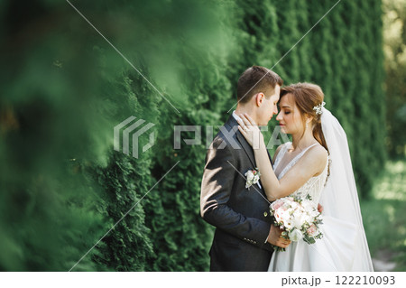 Happy wedding couple charming groom and perfect bride posing in park Happy wedding couple charming groom and perfect bride posing in park 122210093