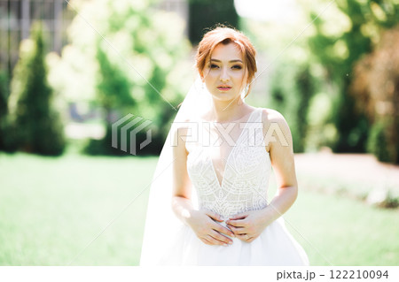 Beautiful bride posing in wedding dress outdoors Beautiful bride posing in wedding dress outdoors 122210094