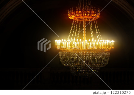 Vintage large chandelier with crystal pendants and yellow glow. 122210270