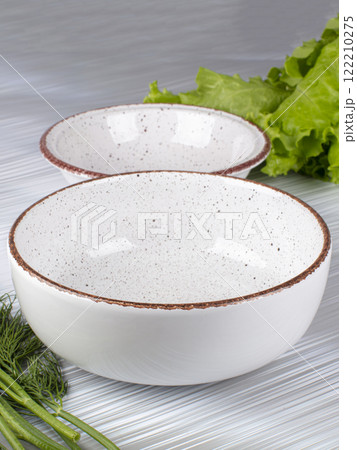 Ceramic clay plate with dark edging on gray background 122210275
