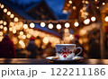Merry Christmas and Happy Holidays. A cup of hot drink and cookies with background of the lights of Christmas market. Cup of coffee on the window sill. Bright lights of the city hristmas background. 122211186