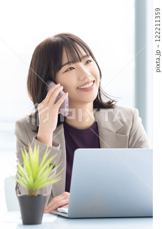 スマホで話す笑顔の女性・ビジネスウーマン 122211359
