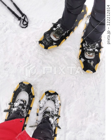 Two pairs of legs in snowshoes on winter landscape ready for an outdoor trek in a snowy environment 122212814