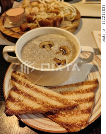 Delicious bowl of creamy mushroom soup with toasted bread served at a cozy restaurant in the evening 122212835