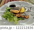 Grilled salmon fillet served with fresh greens and lemon slice on a decorative plate. Healthy lunch. 122212836