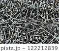 Close-up view of assorted metal screws and bolts scattered on a workbench in a workshop environment 122212839
