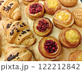 Freshly baked pastries with fruit fillings and chocolate croissants displayed on a wooden board in a bakery 122212842