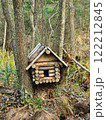 Charming wooden birdhouse log cabin nestled in trees amidst vibrant autumn foliage in a serene forest setting 122212845