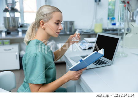 Doctor in laboratory conducting scientific investigation on new medicine using laptop and internet Doctor in laboratory conducting scientific investigation on new medicine using laptop and internet 122214114