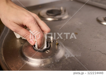 Cleaning a gas stove burner with careful precision is an essential part of kitchen maintenance Cleaning a gas stove burner with careful precision is an essential part of kitchen maintenance 122214440
