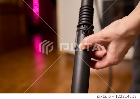 Hands actively using a vacuum cleaner in a clean and modern kitchen environment 122214515