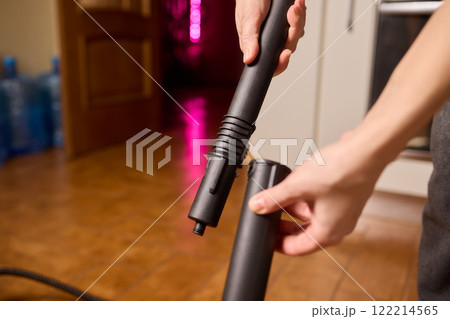 Hands actively using a vacuum cleaner in a clean and modern kitchen environment 122214565