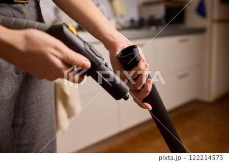 Hands actively using a vacuum cleaner in a clean and modern kitchen environment Hands actively using a vacuum cleaner in a clean and modern kitchen environment 122214573