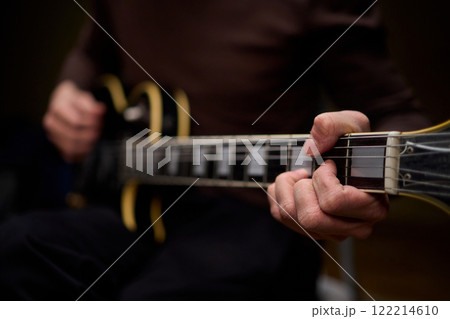 Close Up of Hands Playing a Guitar in a Warm and Cozy Setting Filled with Music and Art 122214610