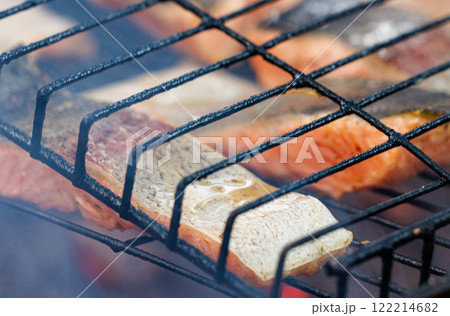 Grilled trout fish sizzling on a barbecue grill during a summer gathering by the lake 122214682