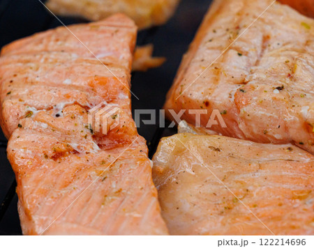 Grilled trout fish sizzling on an outdoor grill under the warm sun during a summer gathering by the lake 122214696