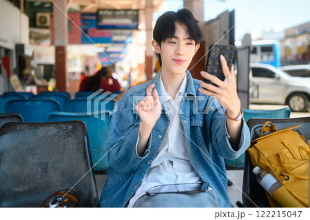 Cheerful young traveler making a video call at in a public transportation terminal 122215047