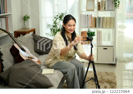 Pretty female vlogger checking smartphone and setting up for record video at home Pretty female vlogger checking smartphone and setting up for record video at home 122215064