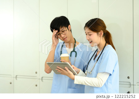 Young female medical student explaining details on digital tablet to her classmate Young female medical student explaining details on digital tablet to her classmate 122215252
