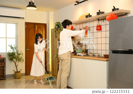 Young adult couple decorating their home with red ornaments for Chinese New Year Young adult couple decorating their home with red ornaments for Chinese New Year 122215331