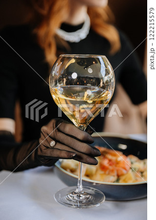 Elegant hand in black gloves holding a wine glass, celebrating luxury and fine dining moments Elegant hand in black gloves holding a wine glass, celebrating luxury and fine dining moments 122215579
