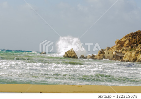 Dramatic Coastal Waves Crashing on Rocks by Sandy Beach Dramatic Coastal Waves Crashing on Rocks by Sandy Beach 122215678