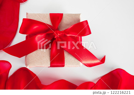 Gift box with craft paper and red ribbon on a white background Gift box with craft paper and red ribbon on a white background 122216221