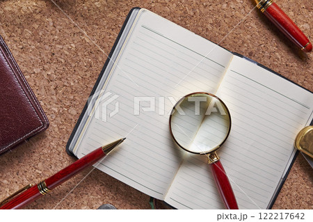 コルクボードの上のルーペと手帳 122217642