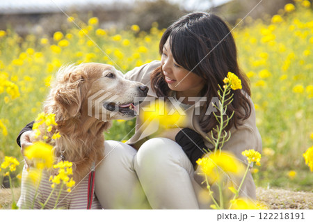 菜の花畑で寄り添う飼い主とゴールデンレトリバー 122218191