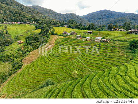 Landscape of green rice terraces and traditional huts in a village near Chiangmai, Thailand. Travel destinations. Beauty of terraced rice fields. Rural life and traditional farming practices in Asia. 122218448