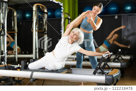 Woman with trainer exercising on Pilates platform 122218478