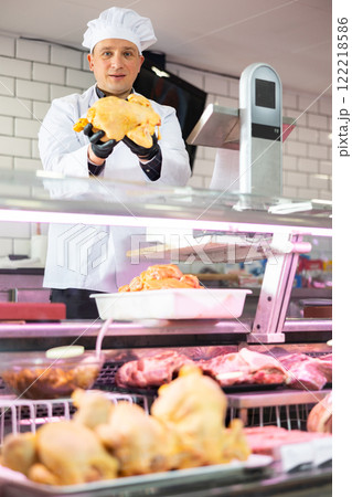 Male butcher showing fresh whole chicken in butchery 122218586