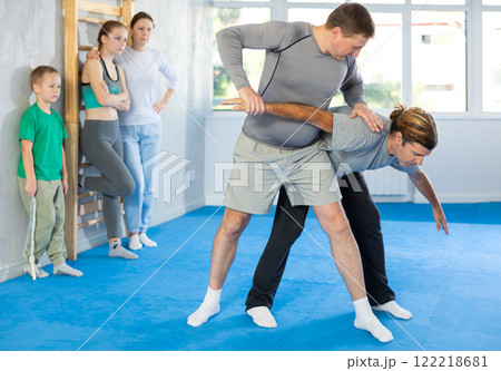 Trainer and man are training in gym practicing hand grab technique 122218681
