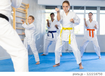 Teen girl with family repeat movements and learn fighting techniques during martial arts lesson Teen girl with family repeat movements and learn fighting techniques during martial arts lesson 122218750
