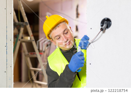 Experienced electrician laying electric wires in building under construction Experienced electrician laying electric wires in building under construction 122218754