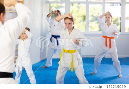 Teen girl with family repeat movements and learn fighting techniques during martial arts lesson 122219029