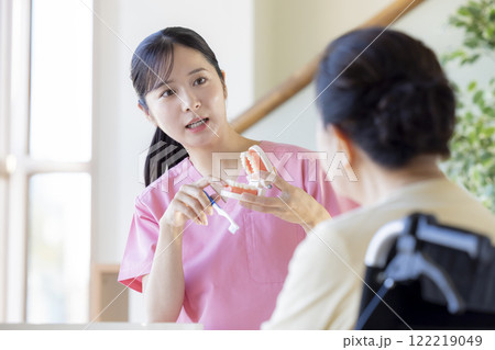歯科衛生士から歯磨き指導を受けるシニア女性 122219049
