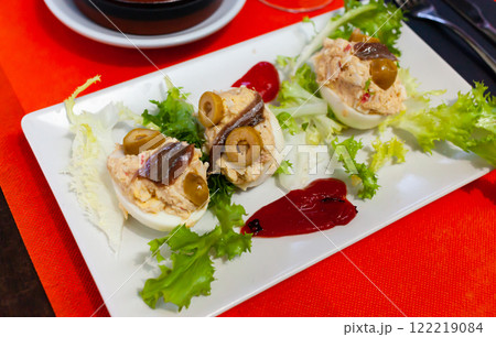 Stuffed eggs with cheese filling and olives, served with lettuce 122219084