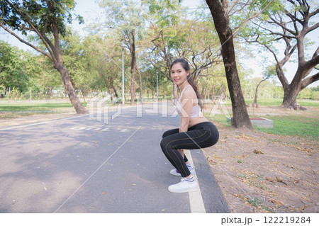 A young woman performing exercise outdoors in a park. A young woman performing exercise outdoors in a park. 122219284