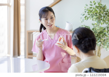 歯科衛生士から歯磨き指導を受けるシニア女性 122219304