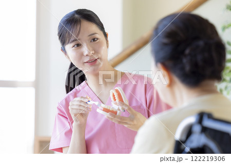 歯科衛生士から歯磨き指導を受けるシニア女性 122219306